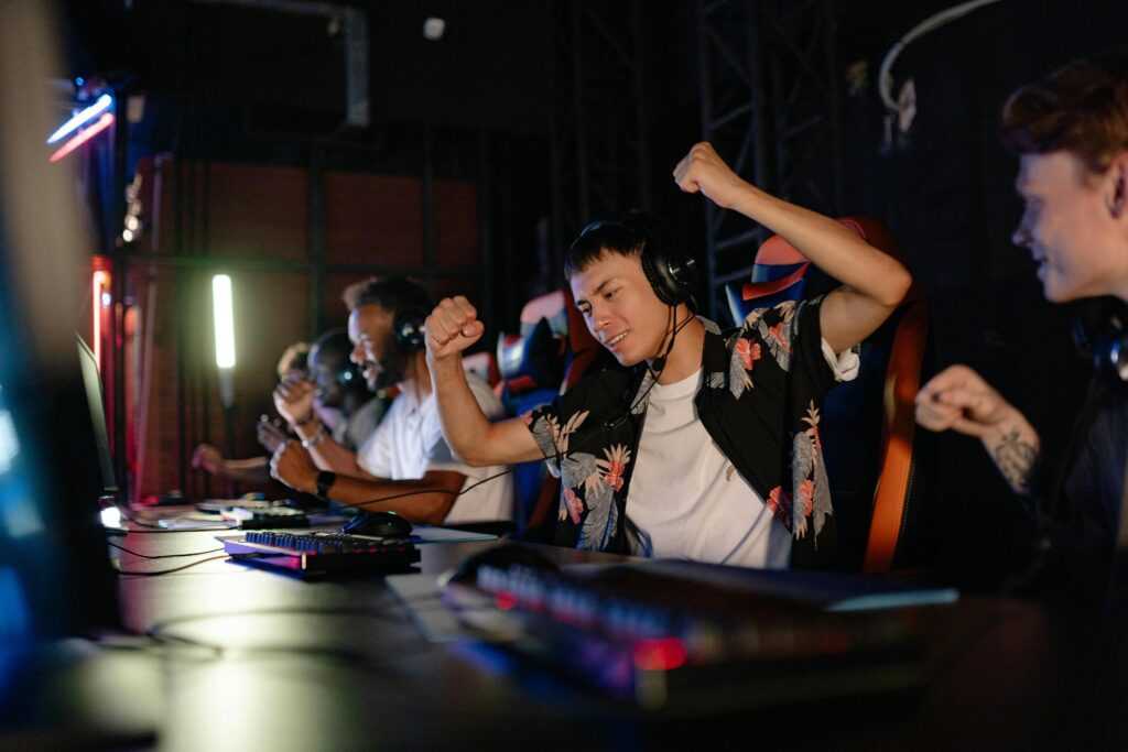 Excited gamers celebrating a win in a competitive gaming tournament with headphones.